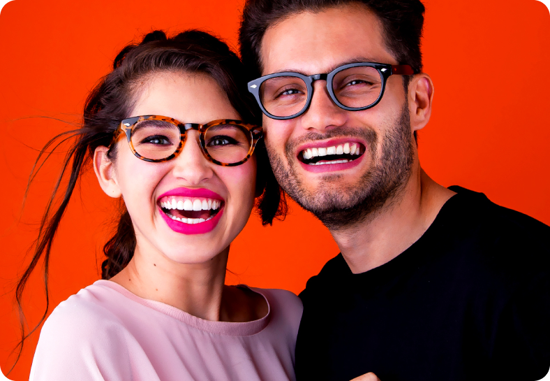 Lifestyle portrait — couple with eyeglasses on an orange backdrop.