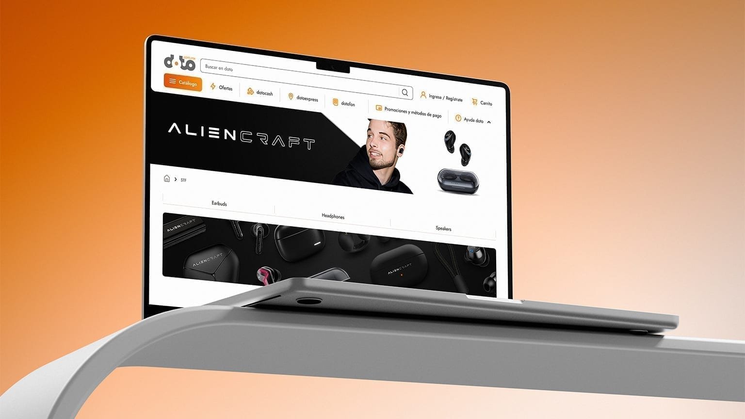Laptop angled on a gray surface showing the Doto desktop AlienCraft brand page with earbuds banner and Earbuds / Headphones / Speakers tabs.
