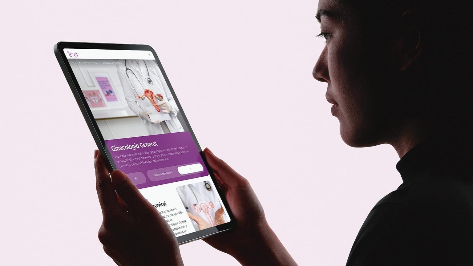 Tablet held in hands showing the Itzel Ginecología General specialty page with a clinical hero and purple description block.