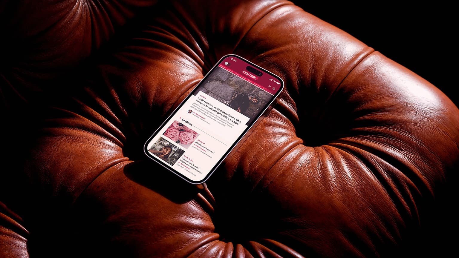 Smartphone with Revista Central mobile homepage on tufted leather.
