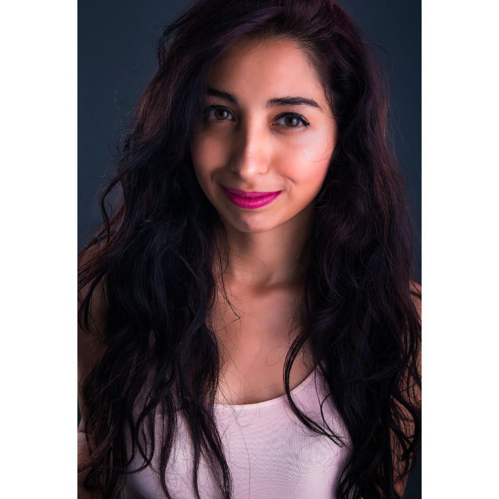 Alondra beauty headshot: pale pink tank top, long wavy hair and magenta lipstick; tight close-up with soft light on dark blue-grey background — professional talent portrait @orquideacsol.