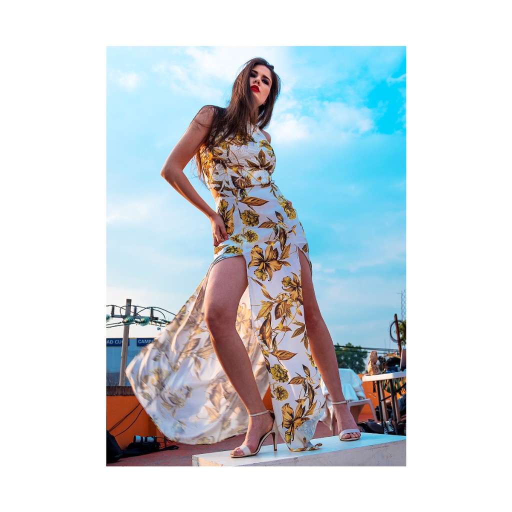 Ferezing rooftop editorial: long white floral dress with high slits, heeled sandals, low angle sky and white ledge.
