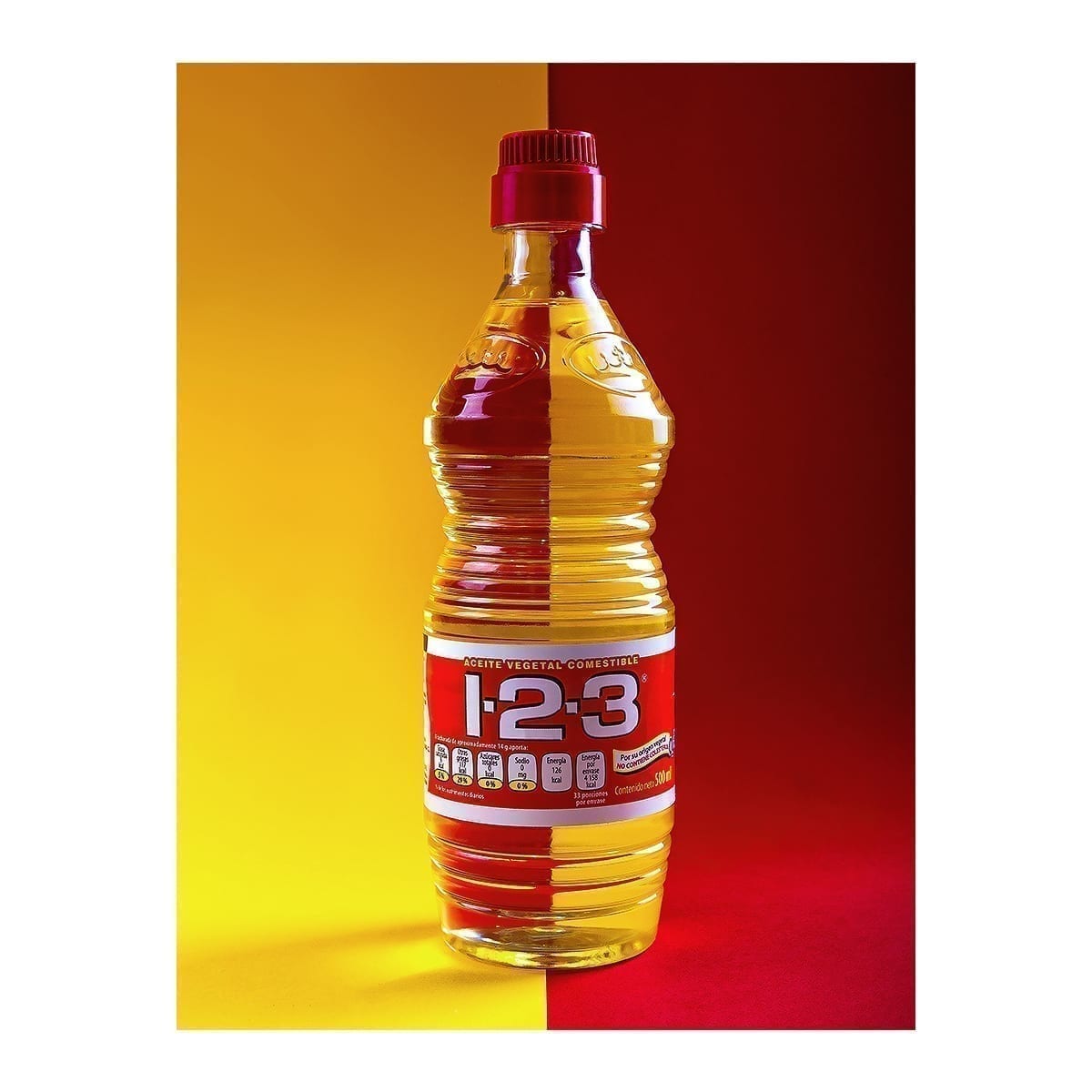 500 ml 1-2-3 edible vegetable oil bottle on a split yellow and red set. “100 Years of History” editorial project, Fábrica de Jabón La Corona — piece 15 of 38.