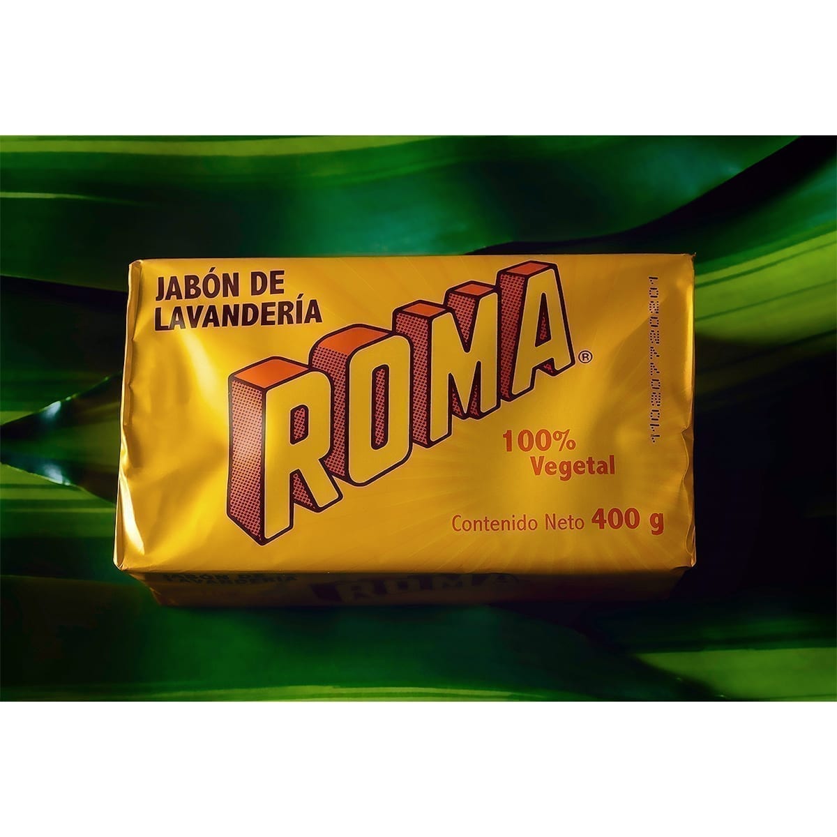 Roma laundry soap bar (400 g) in yellow wrap with dimensional logotype on deep green leaves. “100 Years of History” editorial project, Fábrica de Jabón La Corona — piece 7 of 38.