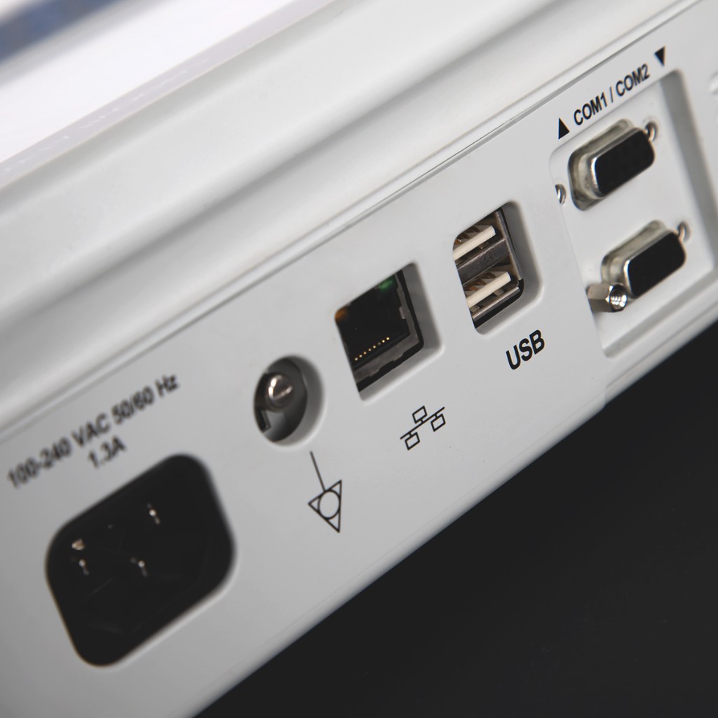 Close-up of the Cardiovit AT-102 G2 rear connectivity: IEC inlet, equipotential bond, RJ45, dual USB, COM1/COM2 serial stack.
