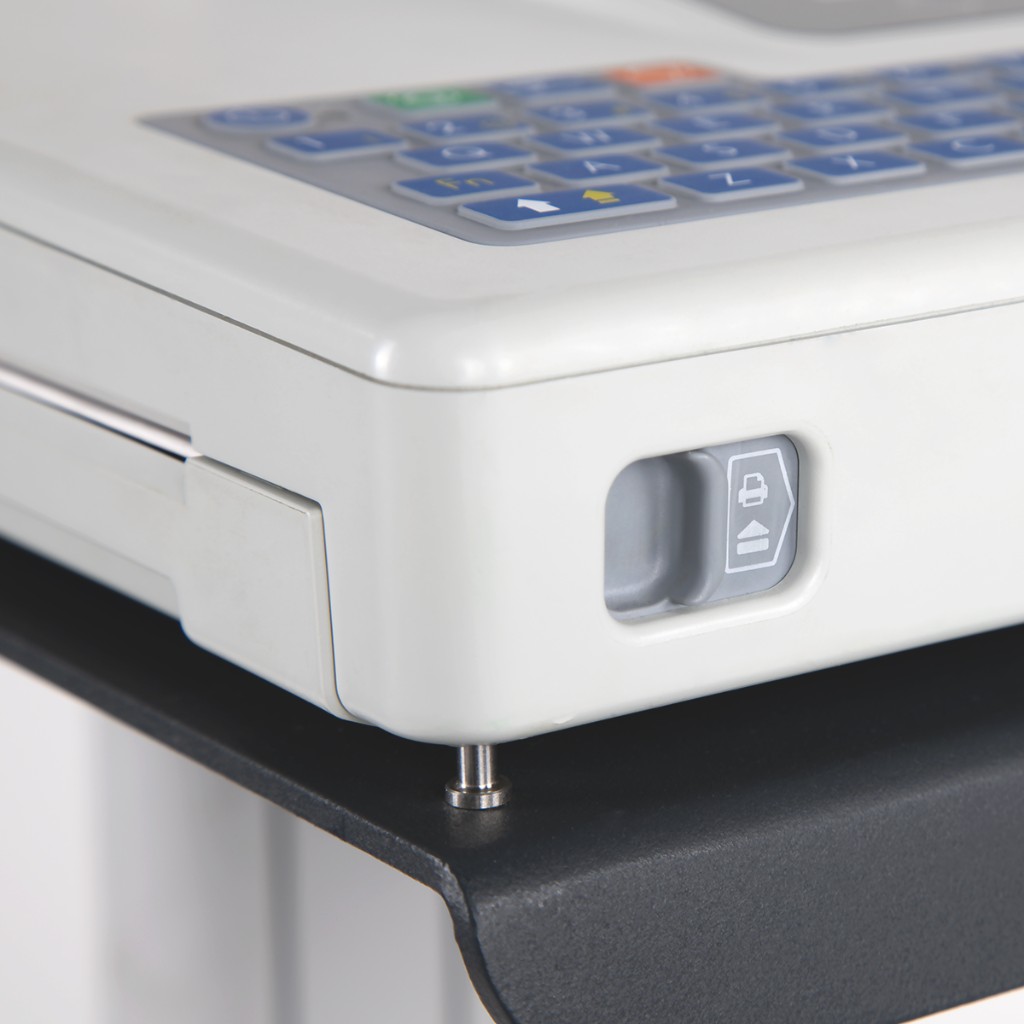 Corner detail of the Cardiovit AT-102 G2: alphanumeric keys and thermal printer door latch — clinical workflow.