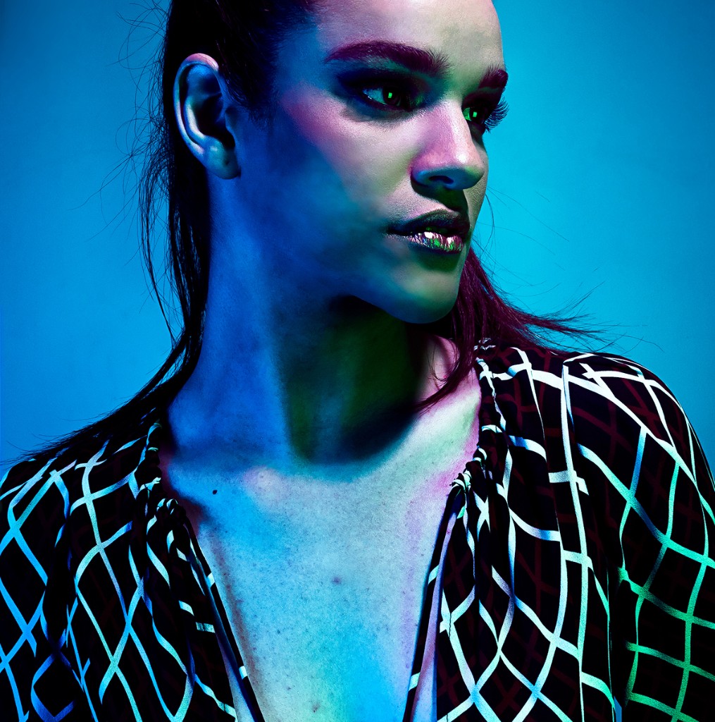 Naty Velázquez editorial profile: blue, green and magenta gel light, geometric grid top, saturated blue background.